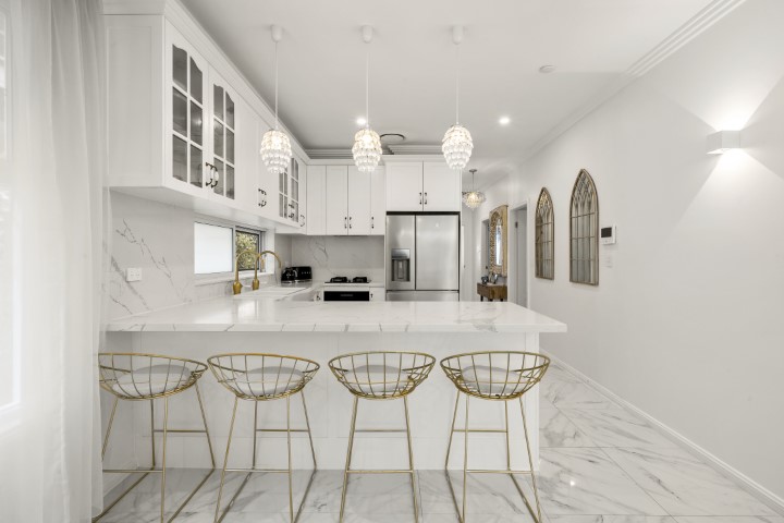 Modern kitchen with three stools, white cabinets, and island counter